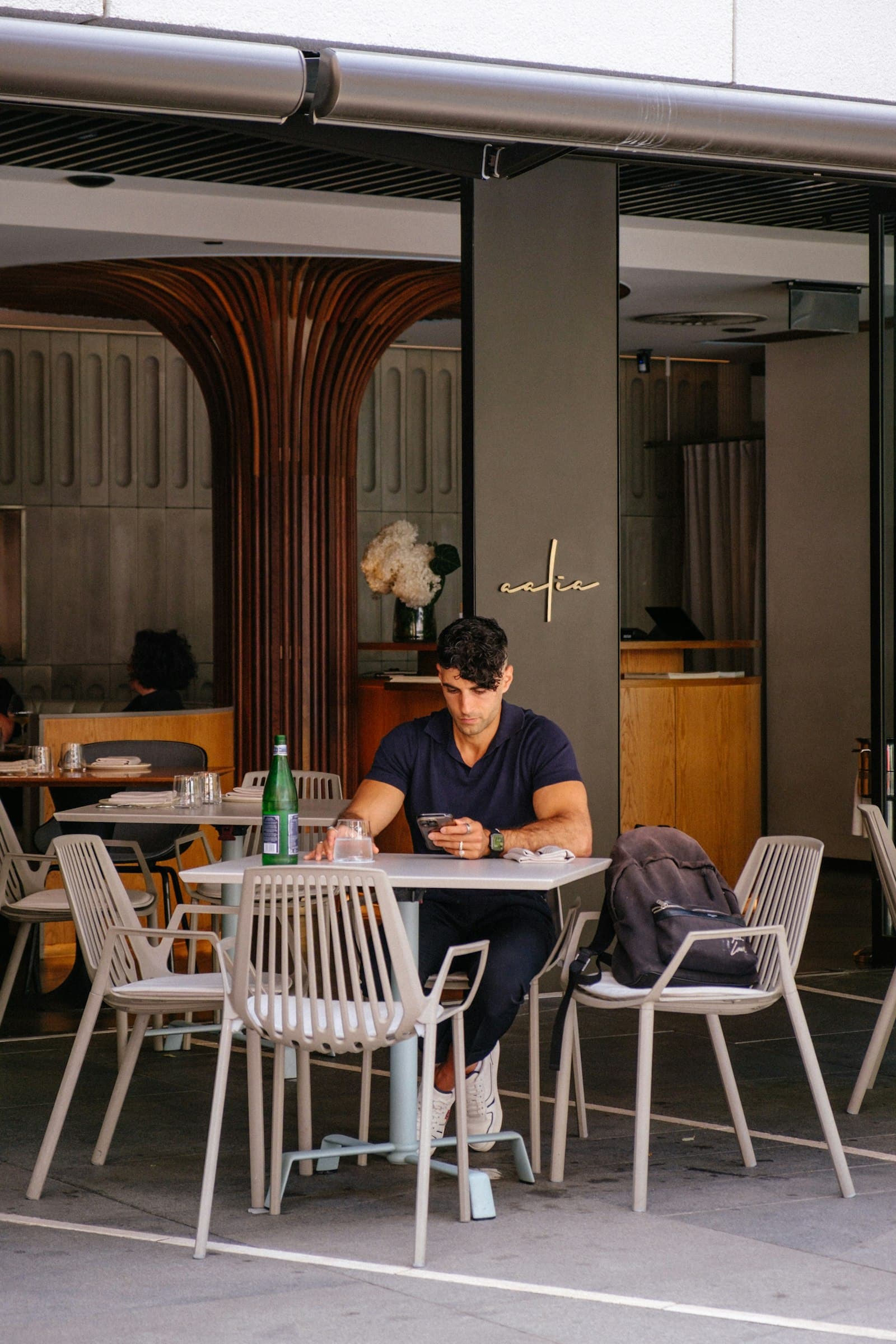 Man sitting at an outdoor cafe table checking his phone