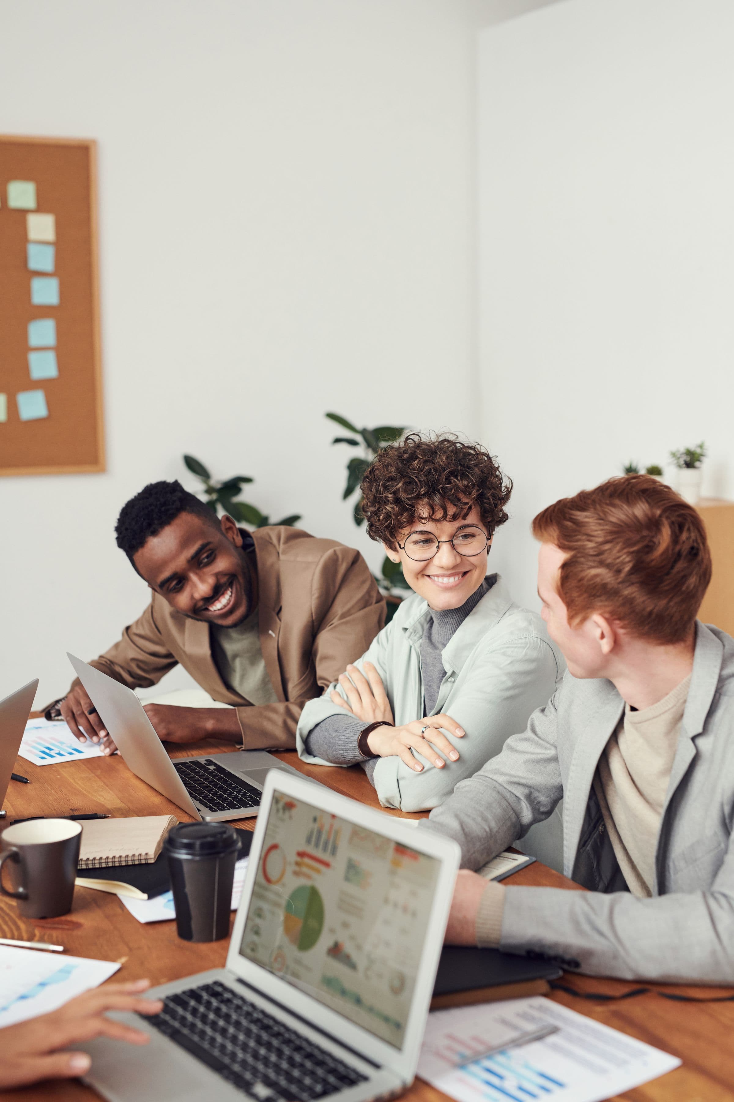 Team of three smiling around laptops in a meeting
