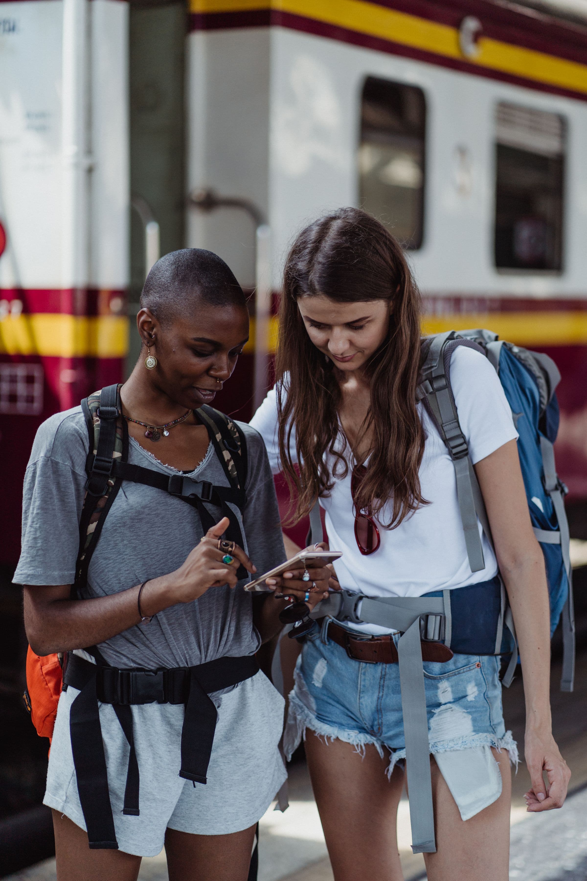 Two friends looking at a phone together at a train station