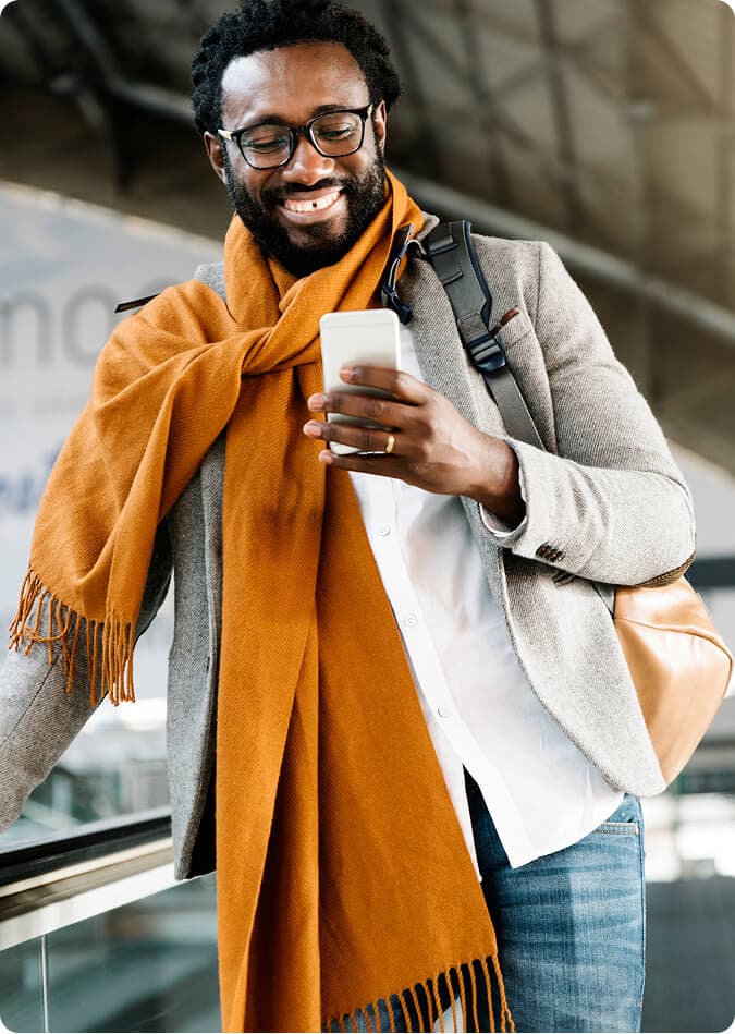 Man smiling while looking at his smartphone on the go